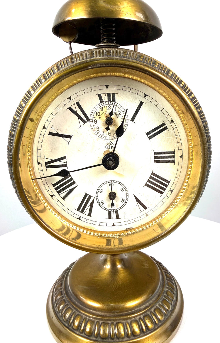 Jahresuhrenfabrik alarm clock displaying the diamond-shaped J–UF manufacturer's trademark on its aged cream-coloured dial.