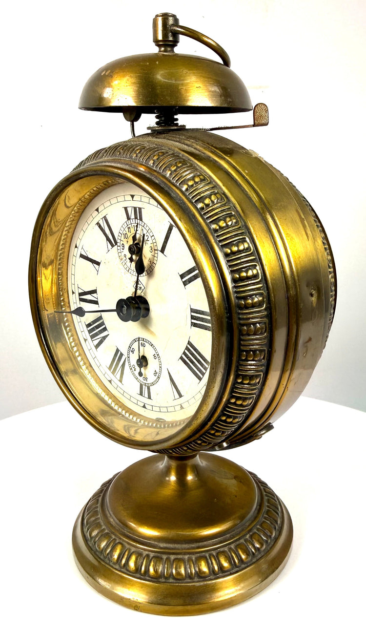 German Black Forest mechanical alarm clock displaying a cream-coloured dial, bold Roman numerals, and traditional black metal hands.