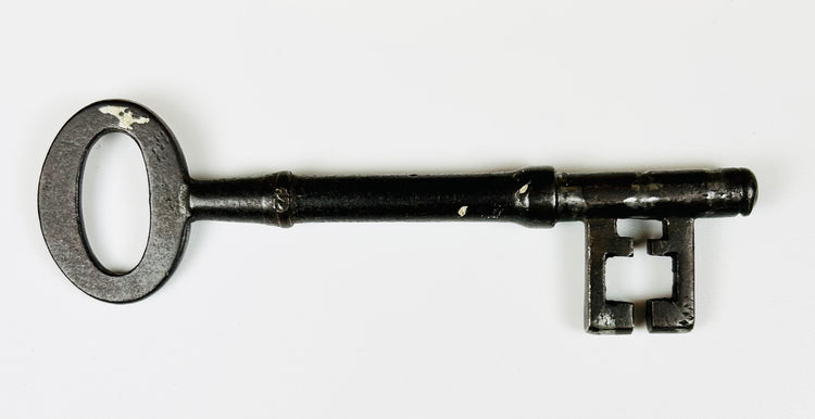 Decorative antique mortise lock with iron key and aged wooden backboard