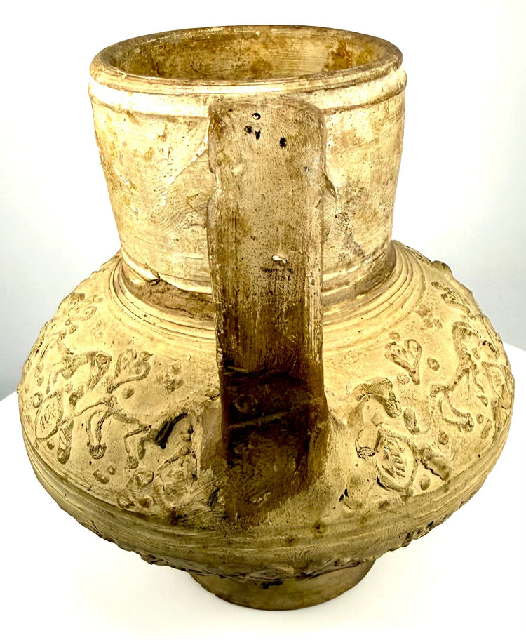 Curved loop handle and cylindrical neck of a medieval Persian-style earthenware ewer, displaying aged surface coloration and wear.