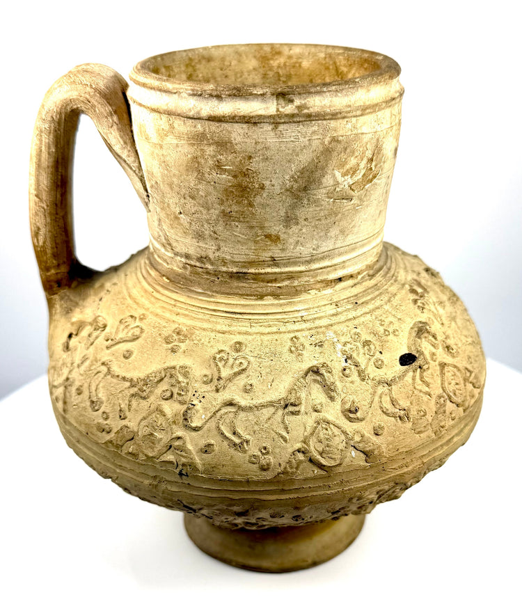 Seljuk-style ceramic ewer with a compressed globular body, pale buff-coloured surface, and elaborate raised relief designs.