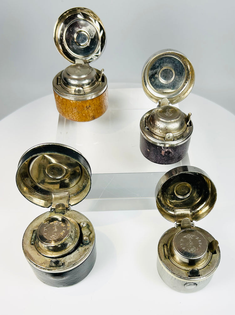 Antique writing accessories featuring glass ink wells and metal casing