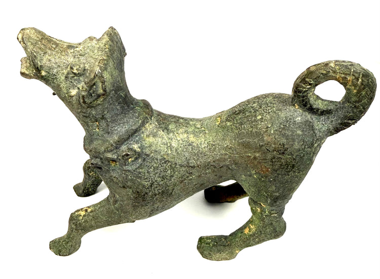 Antique Roman barking dog statuette displaying an elongated body, upright ears, and expressive facial features.