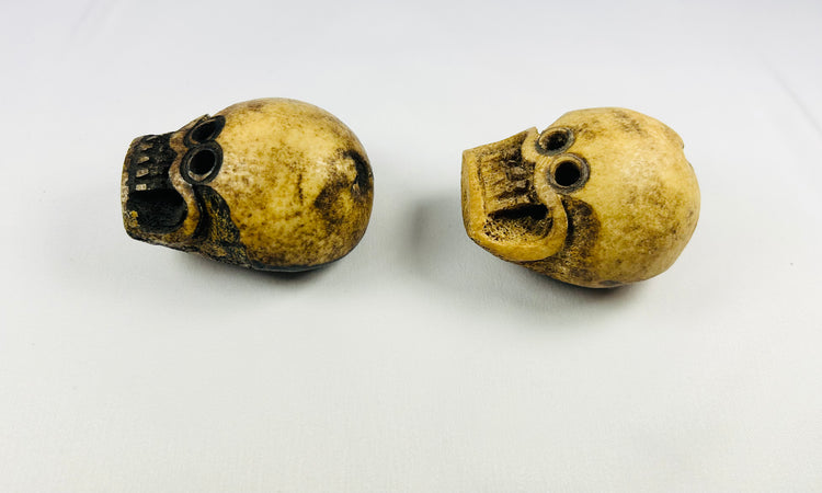 Side profile of Tibetan ritual skull beads carved from human bone, displaying aged patina and vertical suspension holes