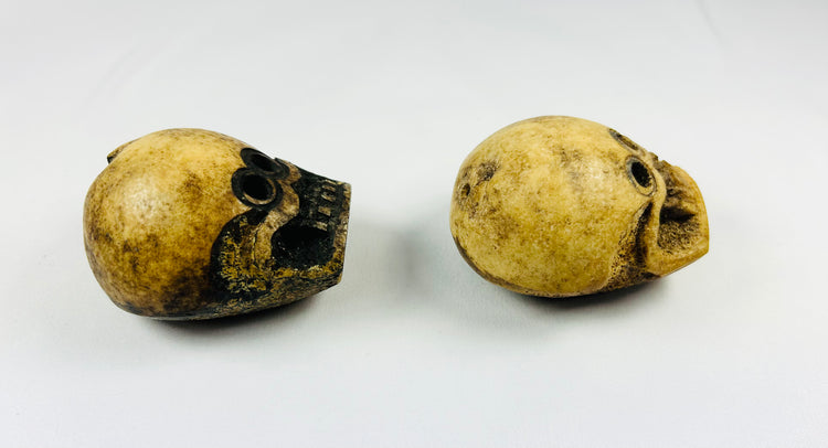 Angled side view of Tibetan Citipati ritual beads showing rounded bone structure, carved facial details, and aged coloration