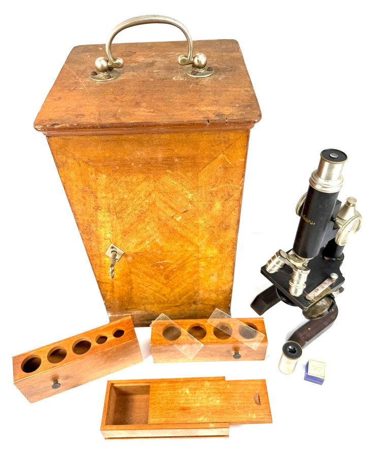 Spencer Lens Company compound microscope displayed beside its wooden cabinet and fitted scientific storage accessories.
