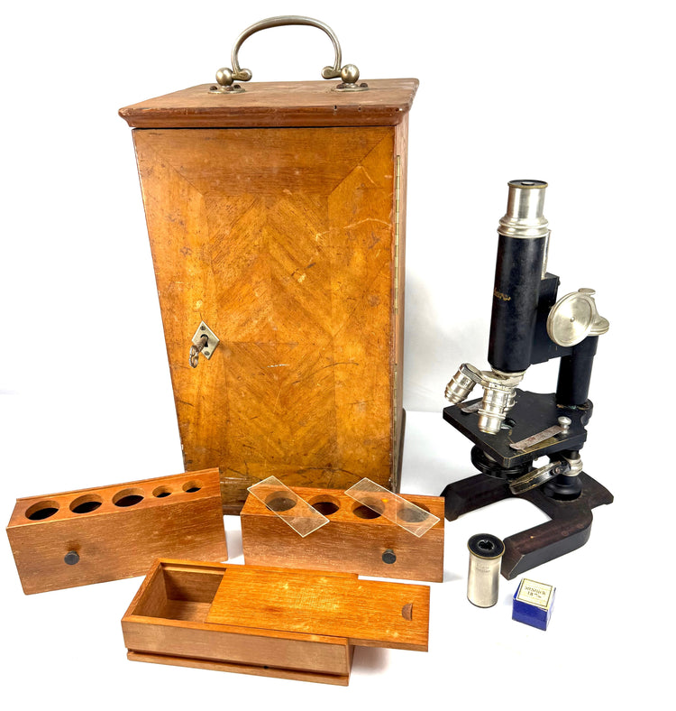 Vintage American Spencer monocular microscope with black enamelled body, nickel-plated fittings, wooden cabinet, and scientific accessories.