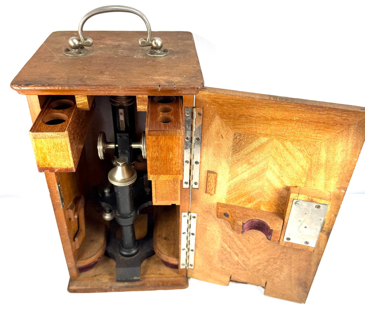 Detailed view of the Spencer laboratory microscope housed inside its original wooden carrying cabinet with hinged door and fitted interior.