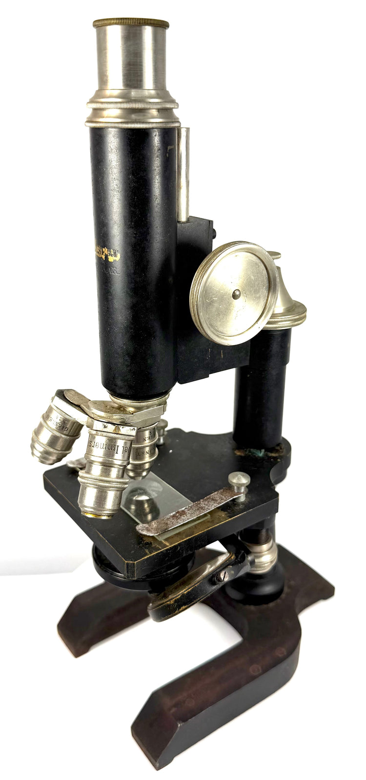 Three-quarter view of an early 20th-century Spencer compound microscope with nickel-plated focusing wheel, triple-objective nosepiece, and horseshoe base.