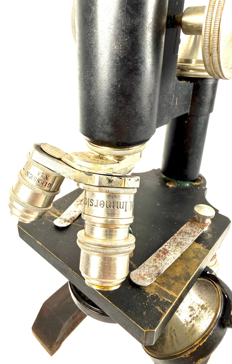 Detailed close-up of the revolving triple-objective nosepiece on an antique Spencer microscope, showing three fitted optical lenses.