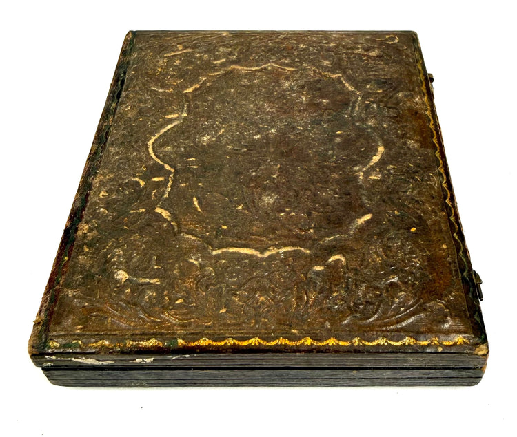 Mid-19th-century hinged photographic keepsake case with textured ornamental exterior, historic surface wear, and decorative borders.