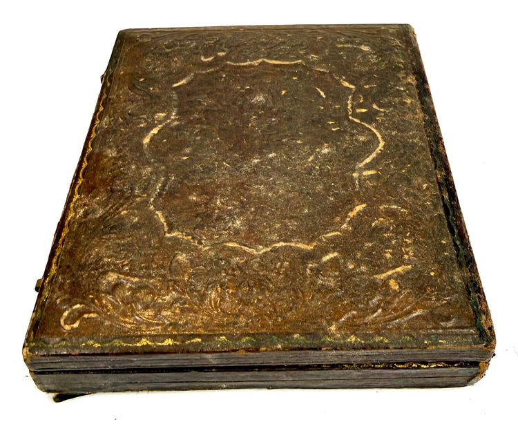 Victorian-era embossed photographic case featuring intricate floral motifs, aged surface patina, and traditional protective construction.