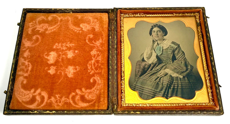 Open 19th-century photographic case featuring a female portrait and richly coloured reddish-orange velvet lining with floral decoration.