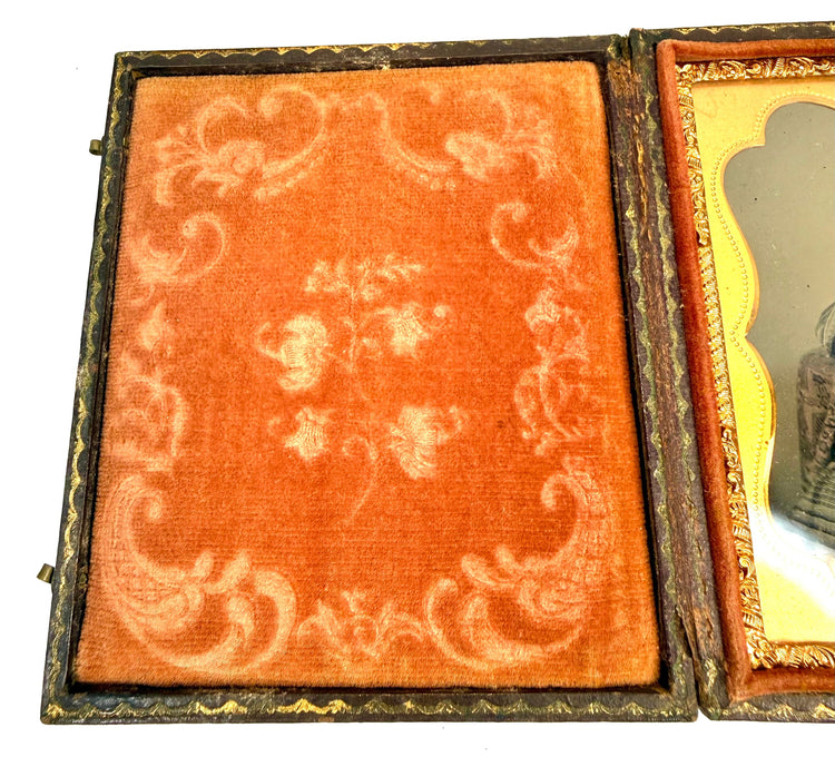 Victorian-era woman's photographic portrait surrounded by an ornate scalloped gilt-metal mat inside a traditional hinged case.