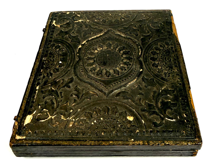 Closed mid-19th-century American photographic case featuring an embossed exterior with decorative medallions and scrolling foliate patterns.