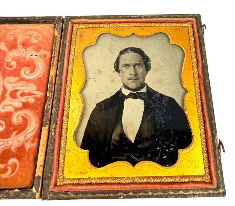 Victorian-era cased photograph of a gentleman showing age-related cracking and darkened areas across the original photographic image.