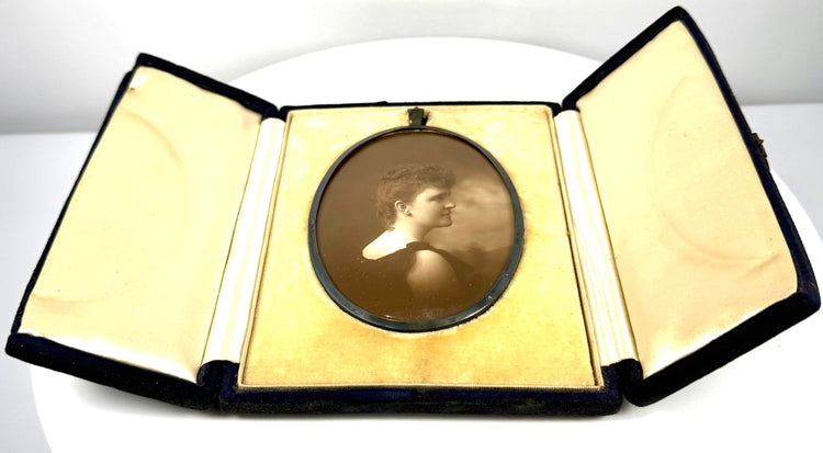 Turn-of-the-century woman's photographic portrait displayed in an open velvet-covered case with decorative cream interior panels.