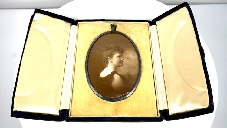 Open three-panel Victorian photographic case featuring an oval portrait of a woman and cream-coloured satin-like interior lining.