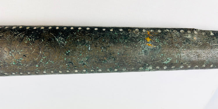 Close-up detail of engraved and dotted ornamentation on ancient Etruscan bronze sword sheath showing fine metalwork craftsmanship, 9th–7th century BCE