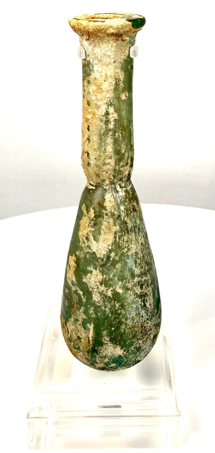 Roman Imperial blown-glass perfume vessel featuring deep olive-green colouring and extensive cream-coloured mineral encrustations.
