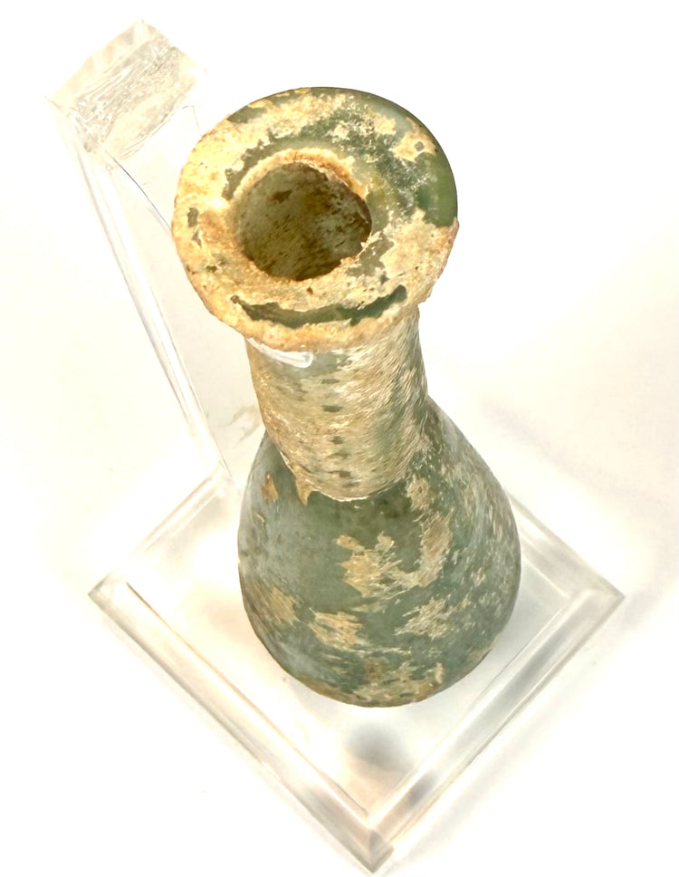 Roman Imperial glass vessel showing areas of emerald-green glass beneath cream-coloured surface encrustations.