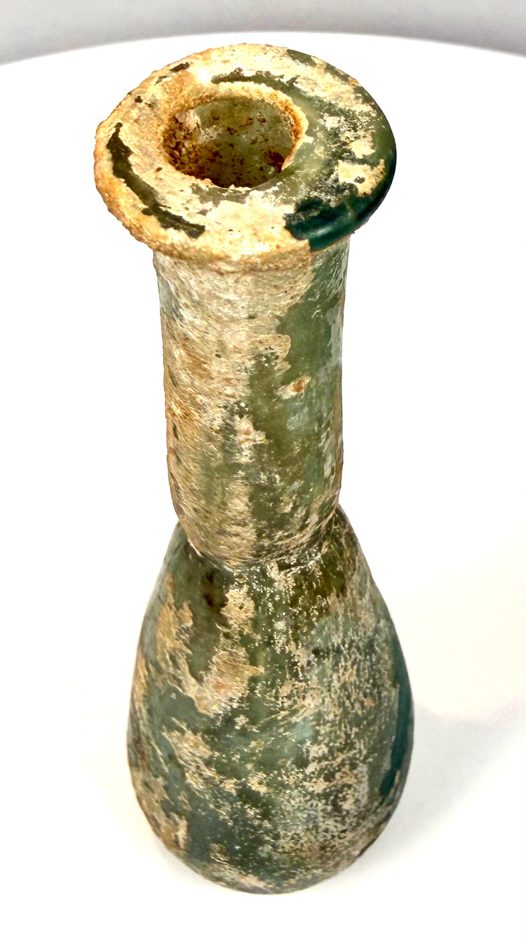Roman Imperial unguentarium with a pronounced circular rim, narrow bottle opening, and naturally irregular glassblown proportions.