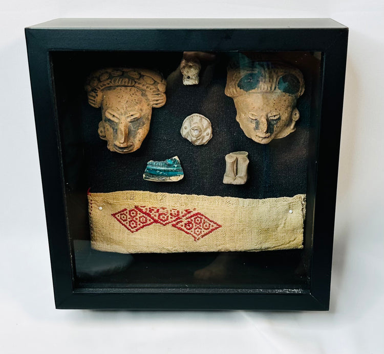 Ancient Mesoamerican artifact display, terracotta and textile pieces mounted in black frame