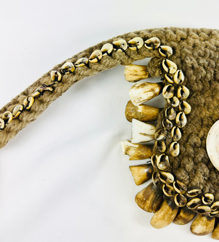 Ceremonial adornment from Papua New Guinea, cowrie shell and animal teeth, displayed on black stand