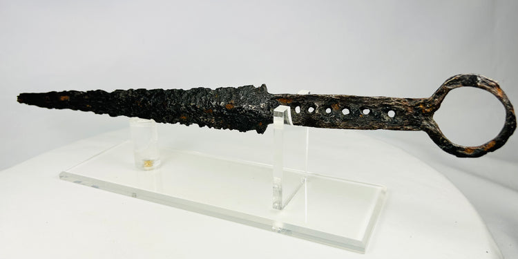 Medieval European dagger with ring pommel and corroded steel blade displayed on acrylic stand — 14th-century artifact photographed on white background