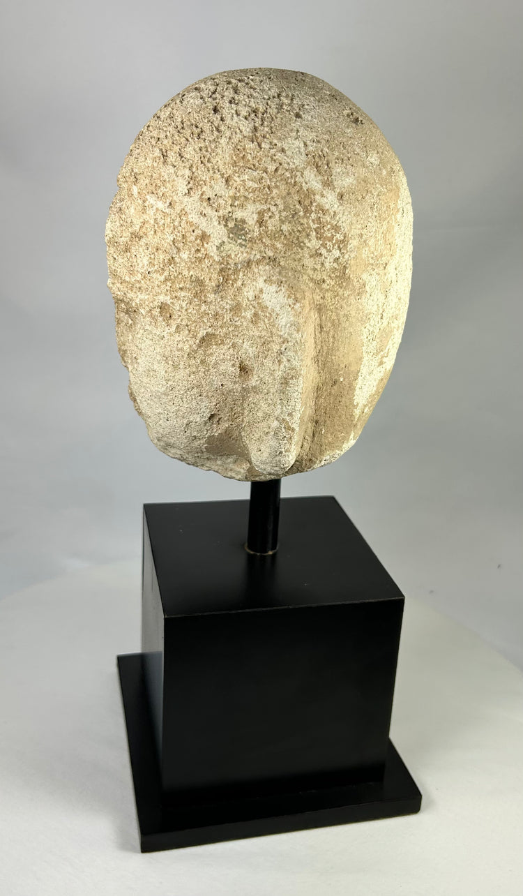 Southeast Asian carved stone Buddha head with serene expression and closed eyes, 13th–14th century, Burma or Thailand, mounted on black display stand.