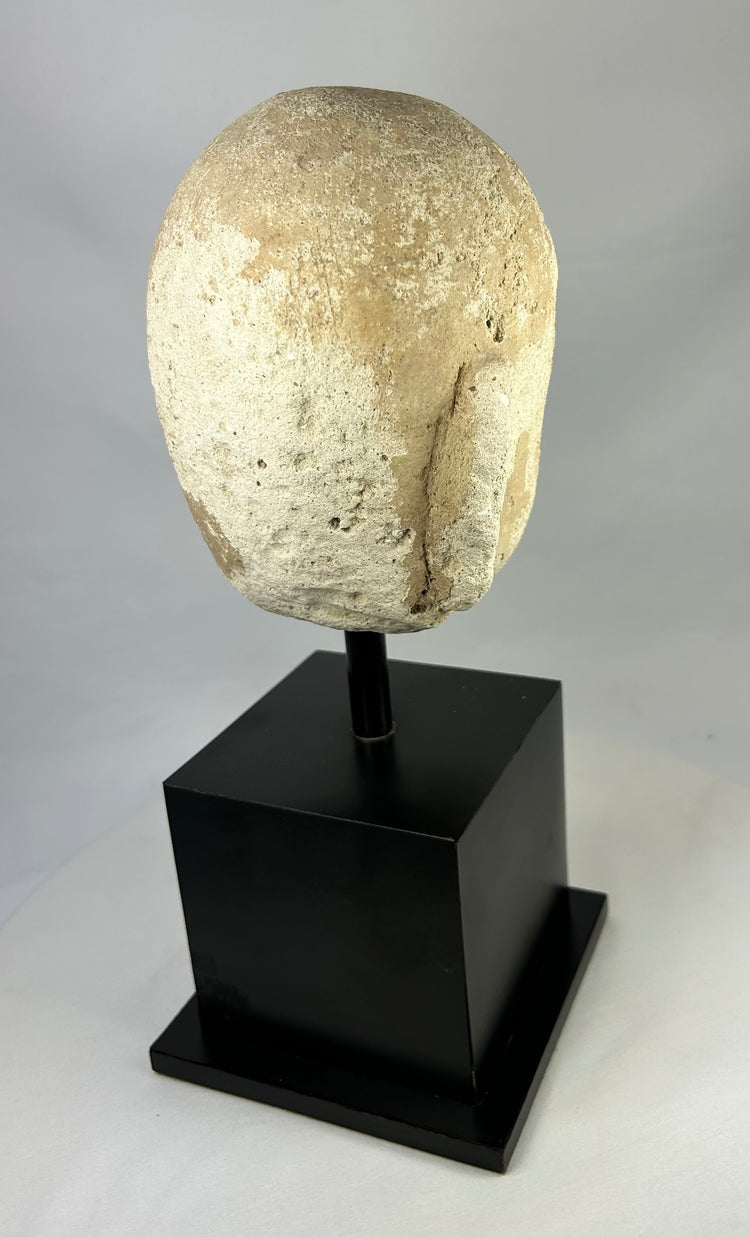 Detailed macro image of Southeast Asian stone Buddha sculpture, 13th–14th century head fragment with meditative features and soft carving lines.