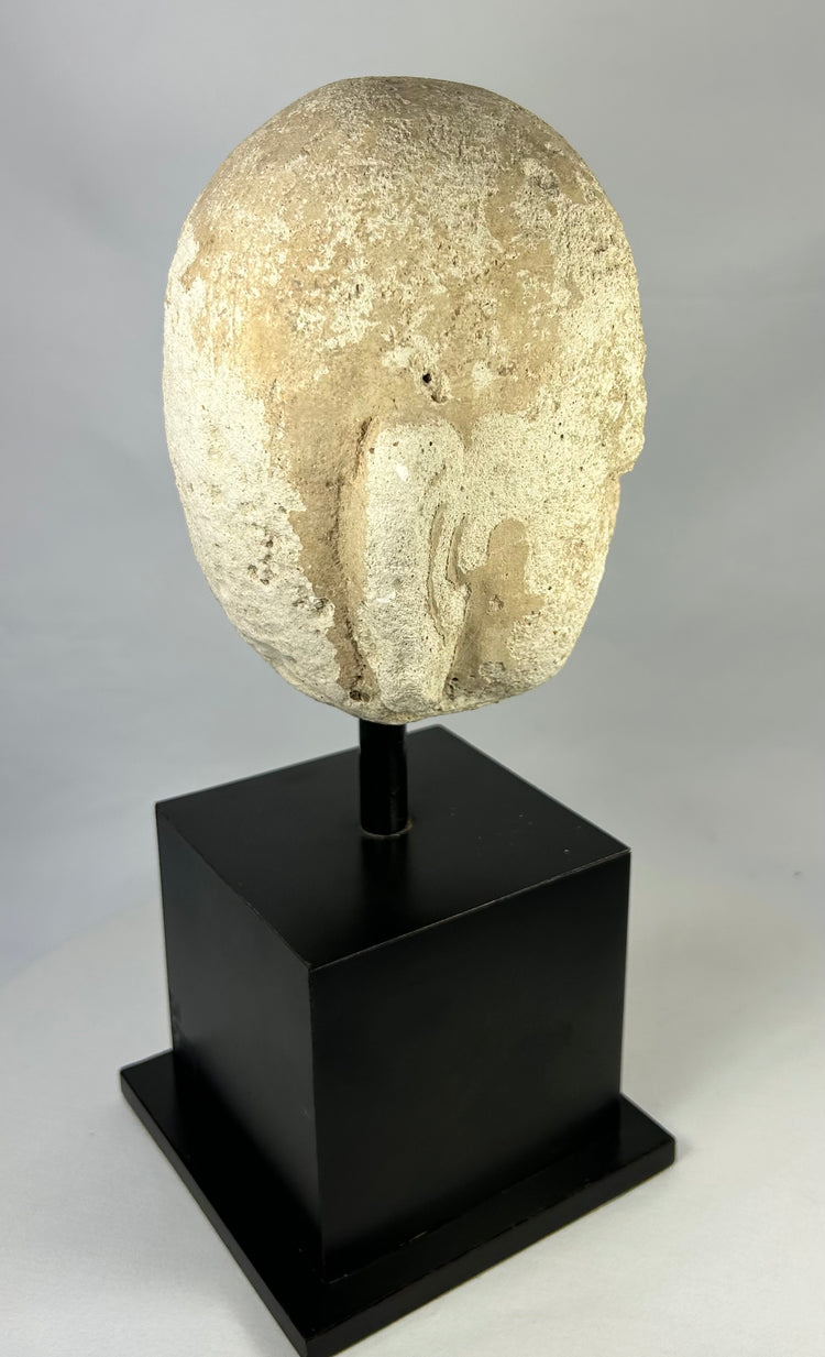 Detailed macro image of Southeast Asian stone Buddha sculpture, 13th–14th century head fragment with meditative features and soft carving lines.