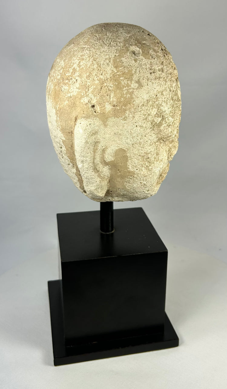 Side view of Southeast Asian carved stone Buddha head, 13th–14th century Buddhist art, mounted on modern black stand, Burma or Thailand.