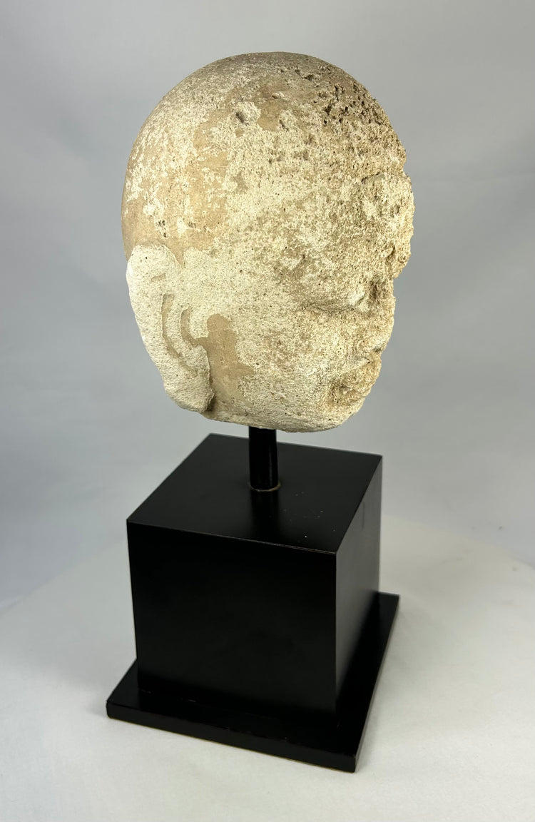 Side view of Southeast Asian carved stone Buddha head, 13th–14th century Buddhist art, mounted on modern black stand, Burma or Thailand.