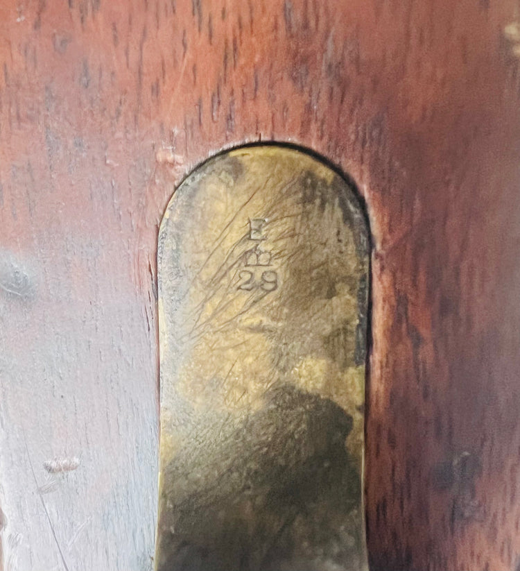 Close-up of engraved brass unit mark inset into the wooden stock of a Victorian-era Snider-Enfield rifle.