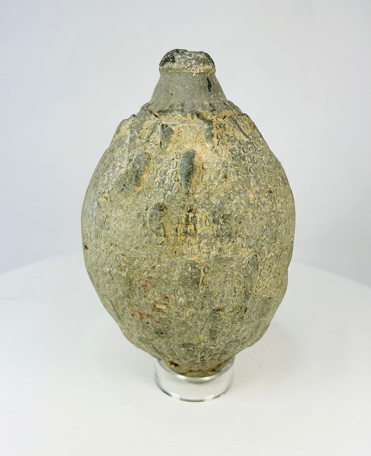 Front view of an Islamic ceramic hand grenade from Greater Persia, 10th–12th century CE, showing its globular form, textured surface, and aged patina.