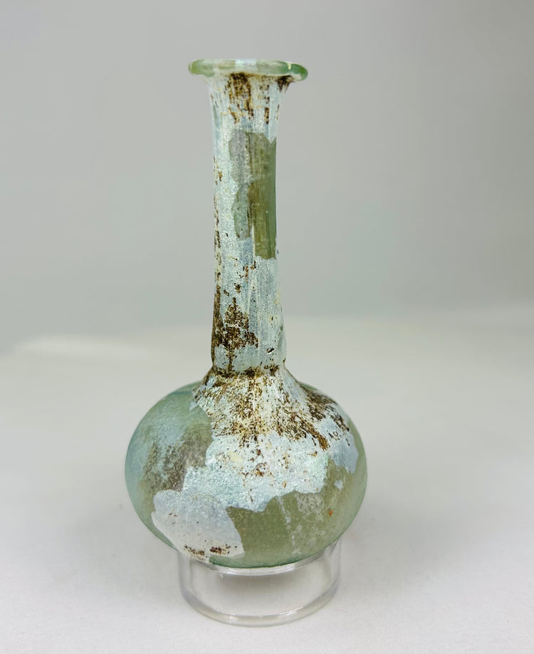 Free-blown Roman glass bottle displaying subtle color variation and natural weathering from burial.