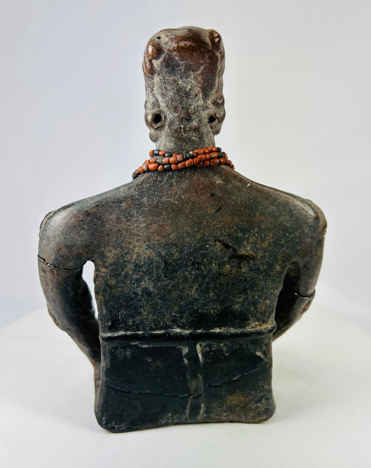 Rear view of Pre-Columbian terracotta figure showing headdress and smooth aged surface texture.