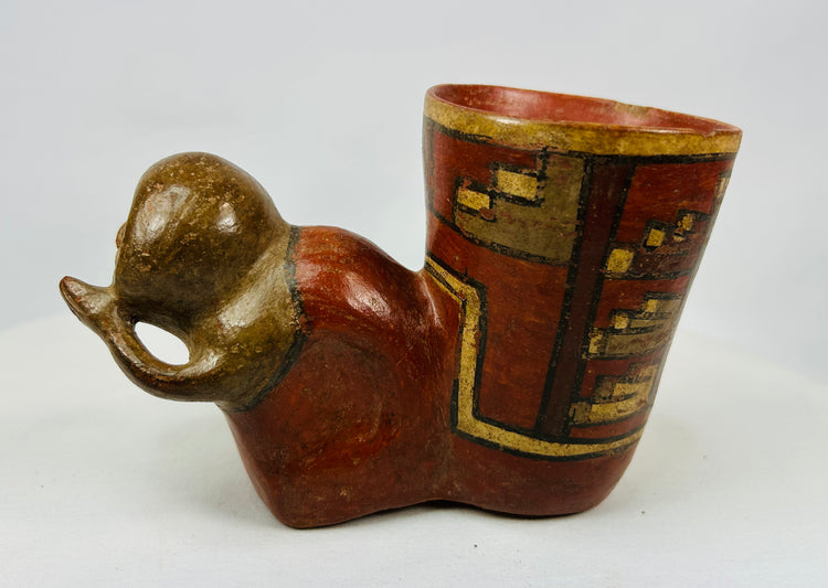 Side angle of ancient ceramic vessel with human head and red slip body decorated with stepped motifs