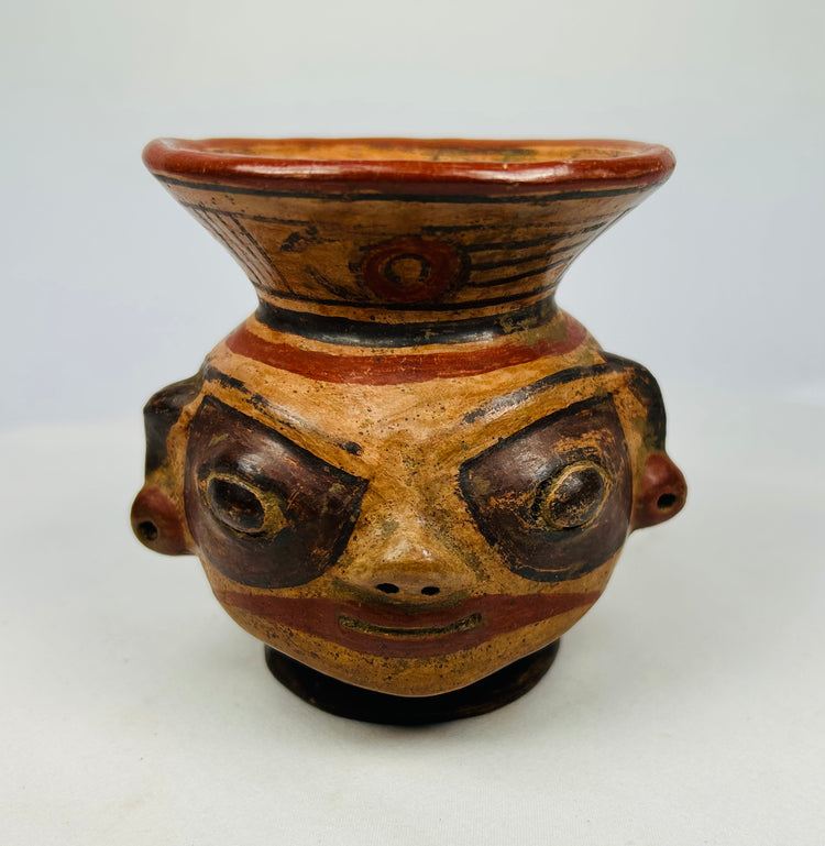 Close-up of Nicoya effigy vessel face with painted eyes, pierced ears, and mineral pigment highlights