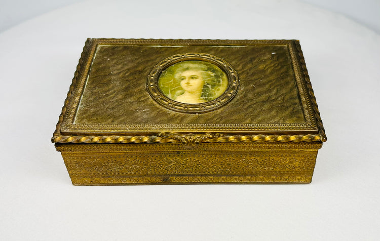 Antique gold jewelry box with oval portrait miniature of a woman displayed on a white background.