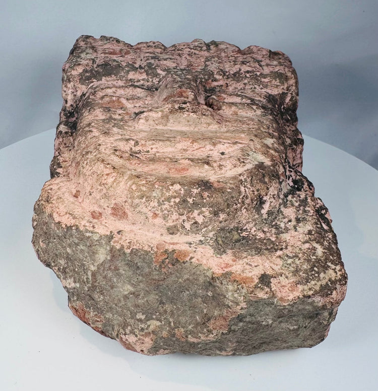 Weathered Mesoamerican stone carving with archaeological deposits