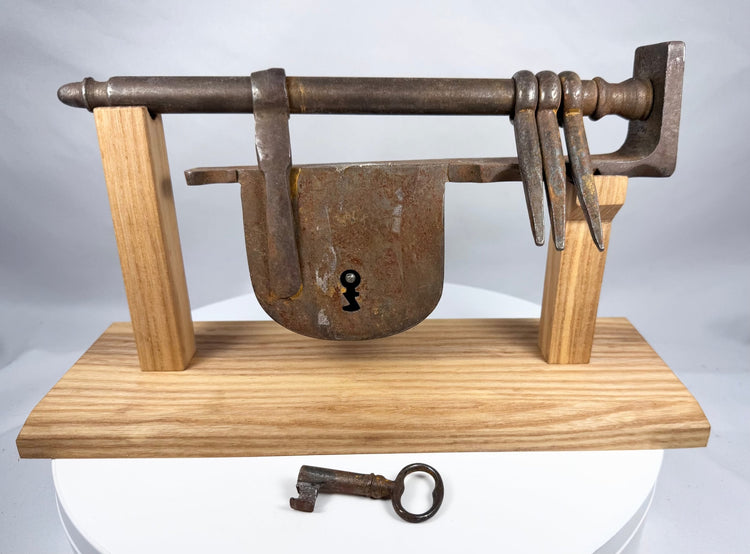 Antique warded iron key beside an 18th-century sliding hasp door lock