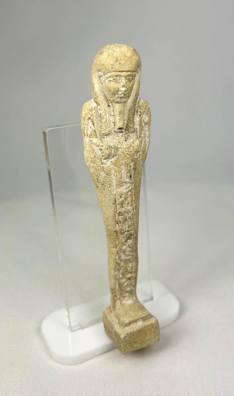Profile view of a carved limestone ushabti with mineral surface deposits