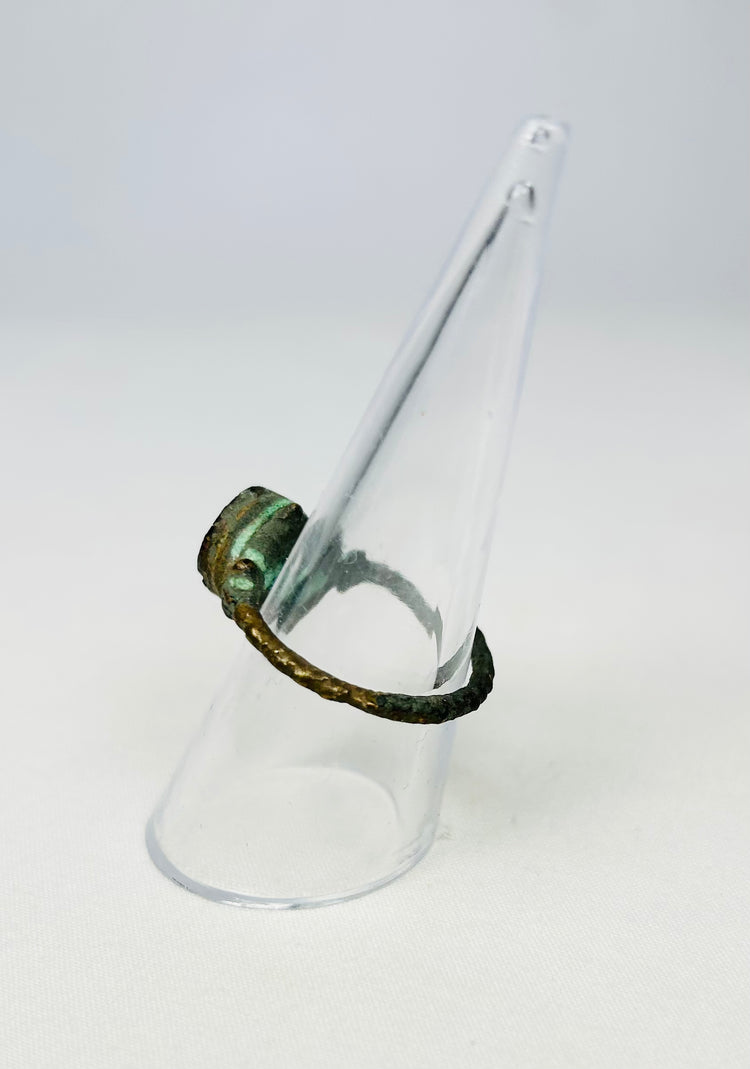 Side profile of a corroded bronze ring showcasing aged metal texture