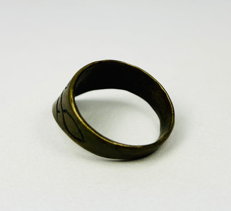 Close-up of engraved motifs on brass thumb ring