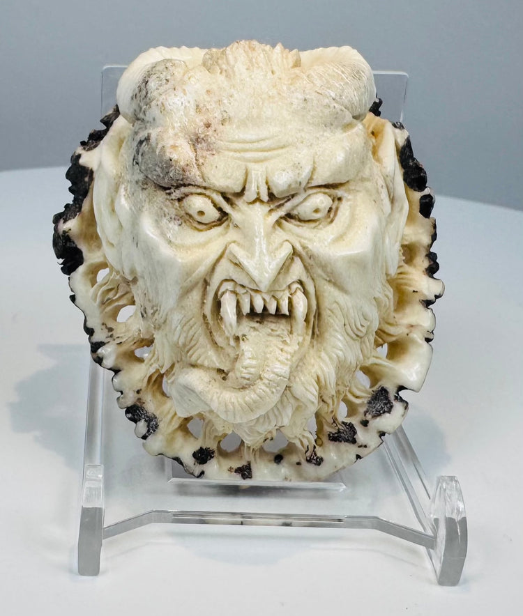 Japanese oni face carving with fangs, horns, and extended tongue
