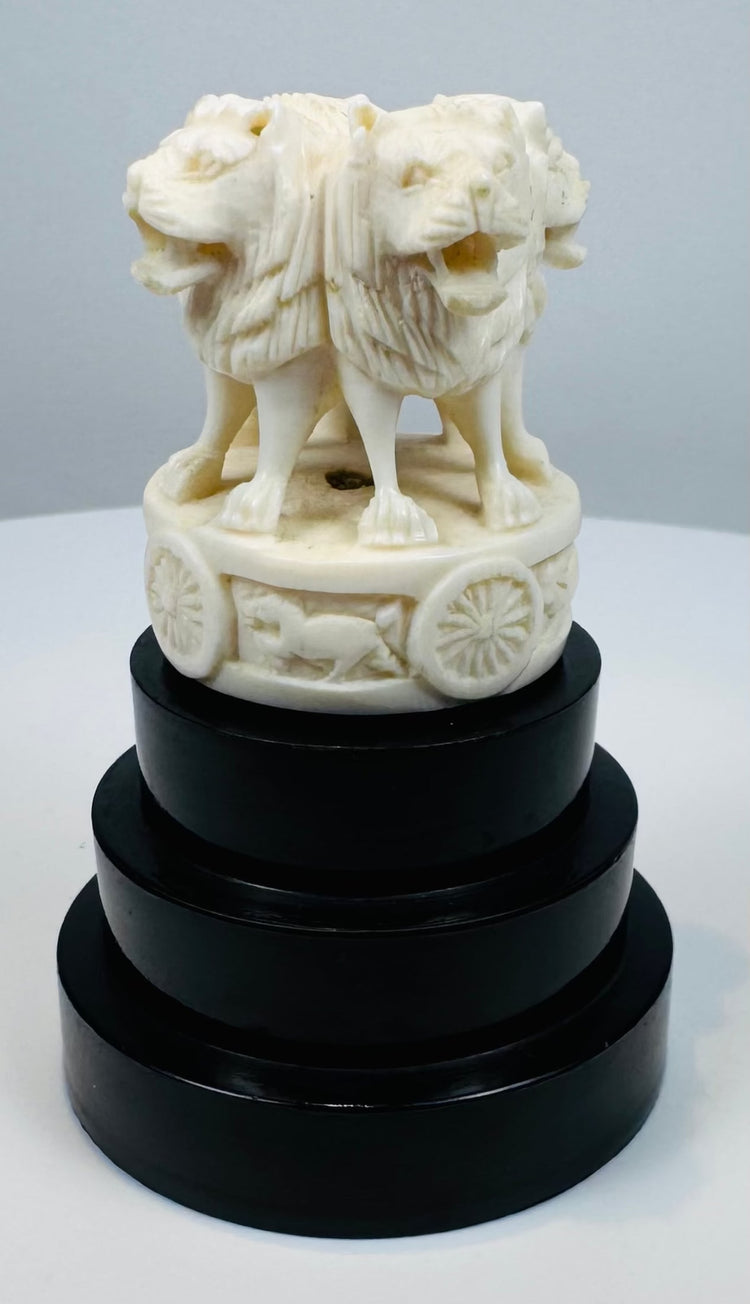 Pale bone-like Ashoka lion sculpture mounted on an ebonized pedestal