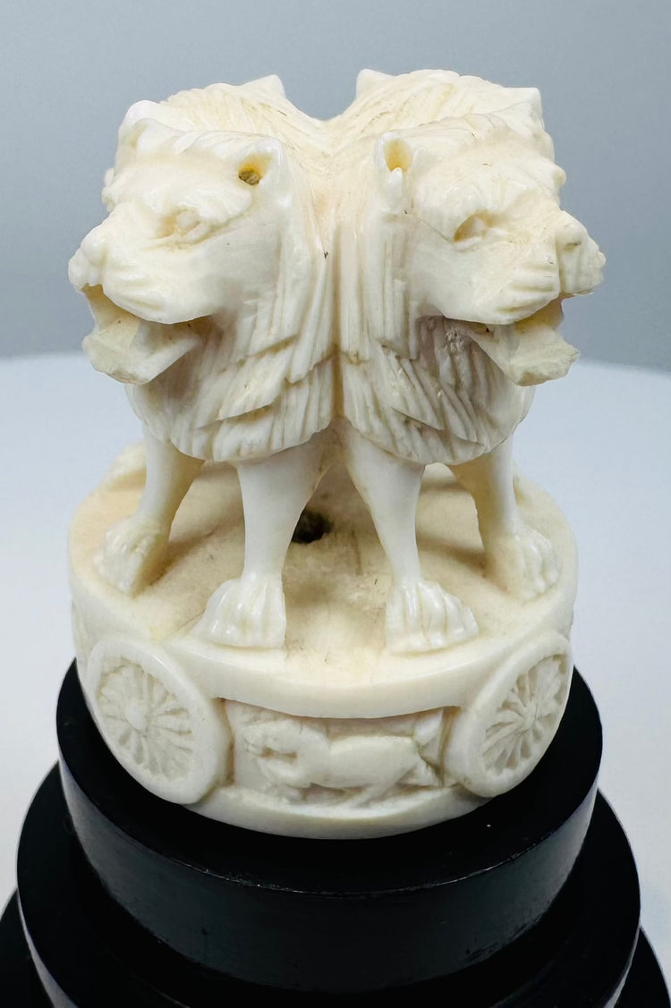 Carved Ashoka lions with dharmachakra motifs on a tiered black base