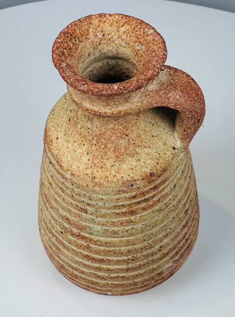 Base view of a Roman terracotta juglet showing its recessed circular foot and aged deposits